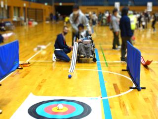 スポレクの様子。レクリエーションのボッチャ体験で、車いすの方が補助具をつかってボールを転がしている。